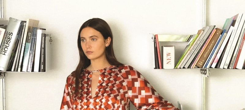A woman leaning on a bookshelf