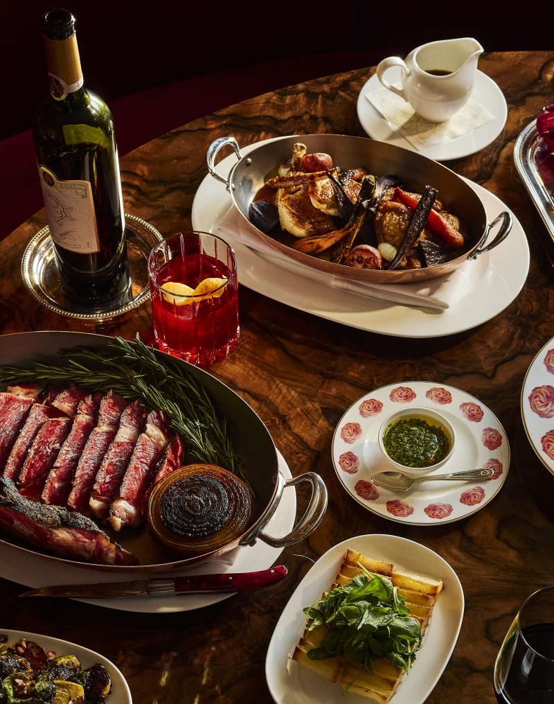Thanksgiving dishes plated on rose plates with meat and wine