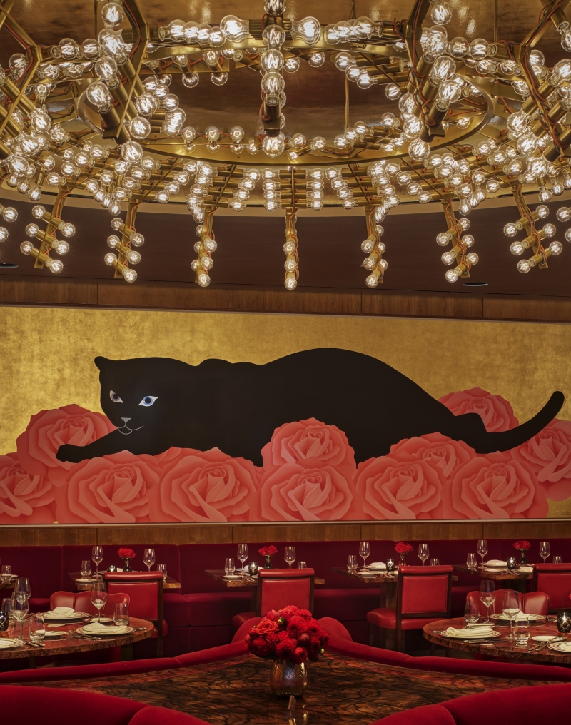 The dining room at La Boca, with gold walls and a mural of a black cat