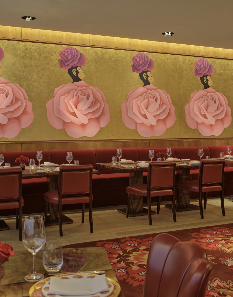 The dining room at La Boca, with gold walls and a mural of white pink roses