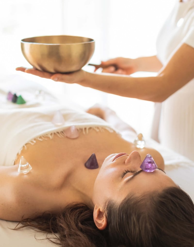 woman lays on table receiving crystal treatment by spa worker