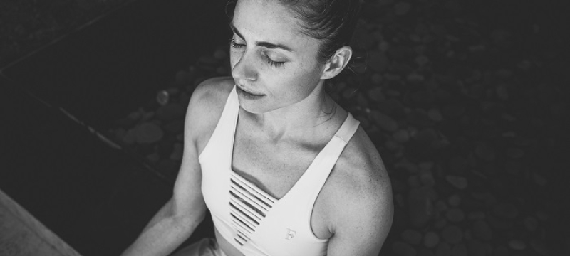 woman sits in meditative pose with eyes closed
