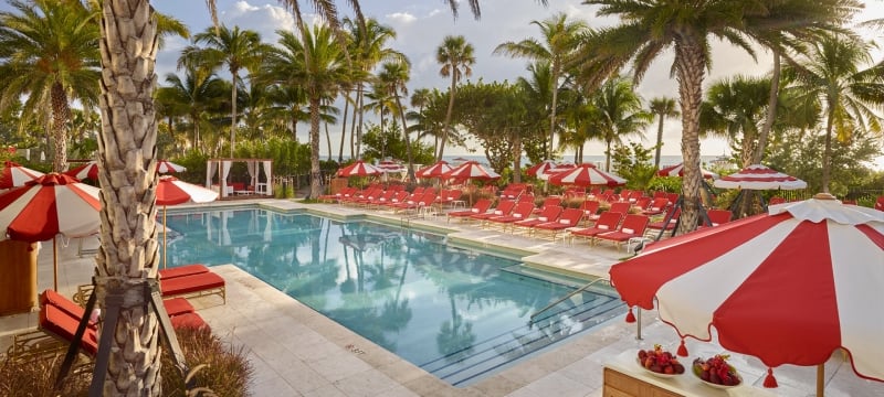 hotel pool surrounded by palm trees and umbrellas