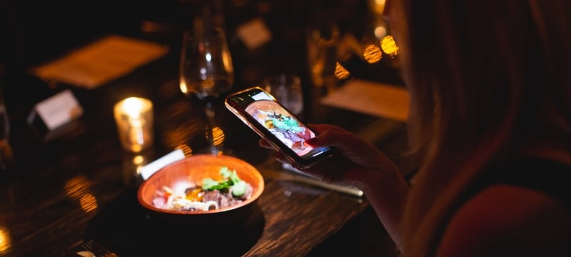 woman taking a photo of her meal at la cava