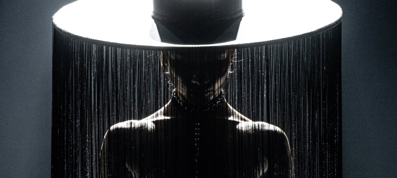 An artistic photograph of a person in a large brimmed hat with fringes