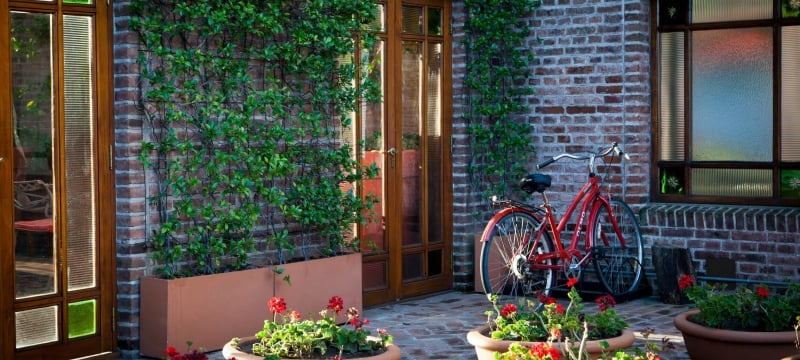 bicycle sits against brick wall exterior of building 