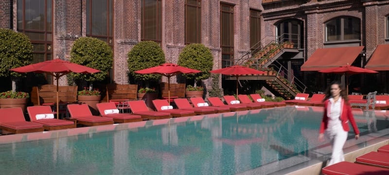 hotel staff walks by a pool with lounge chairs 