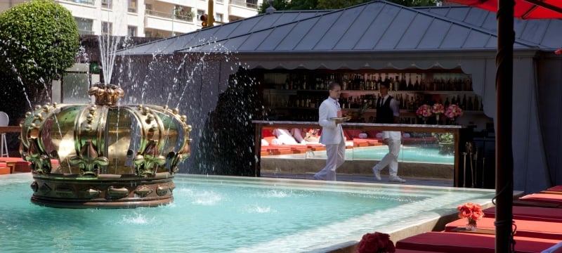 waiter walks by a poolbar with a fountain