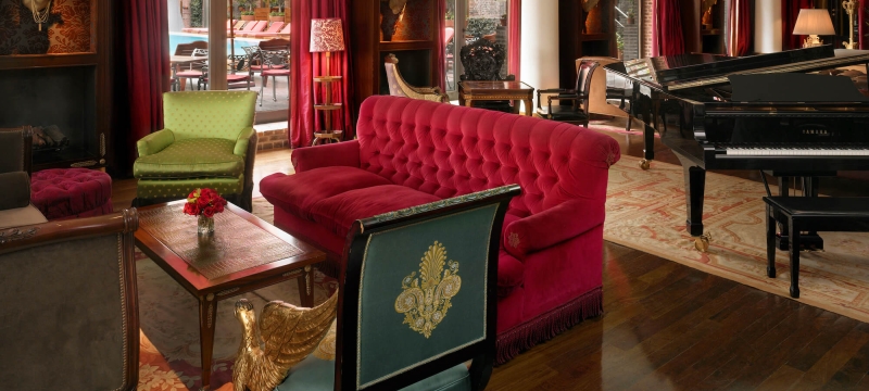 green chair and red couch sit beside piano in lounge