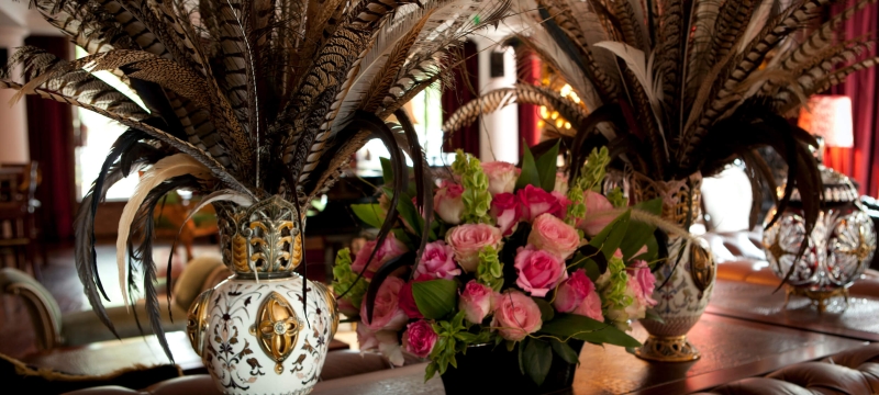 three feather-filled vases flank a flower arrangement on table 