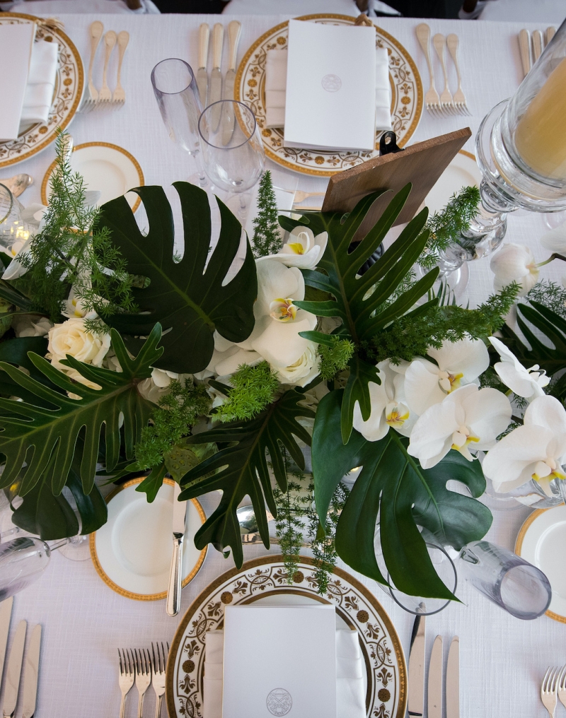 A formal table setting with white tablecloth, flowers, plates, glasses, and silverware