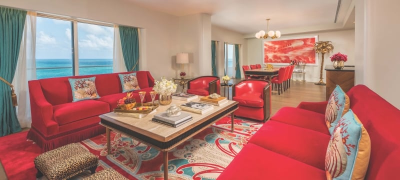 interior of sitting area with red couches, leopard print foot stools and the ocean visible through large window