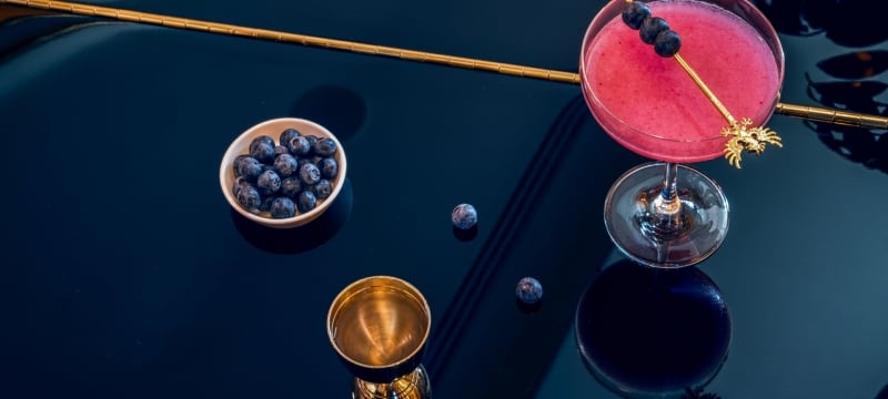 Saxony Bar pink cocktail with dish of blueberries