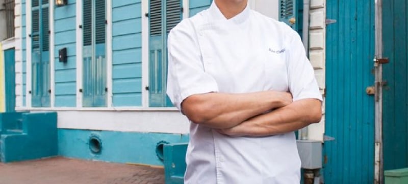 woman with arms crossed stands in street wearing chef's coat