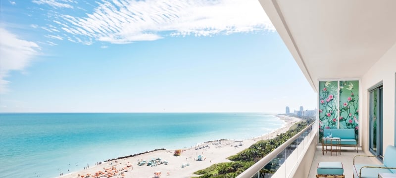 turquoise furniture sits on balcony with beach in the background
