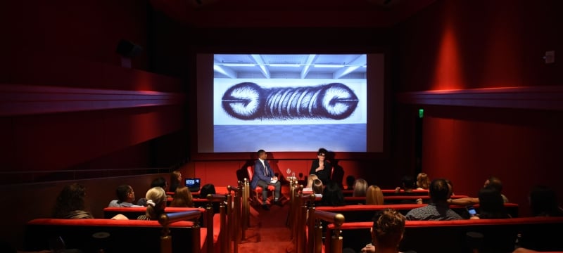 interior shot of performance in screening room with people in seats and projection on screen