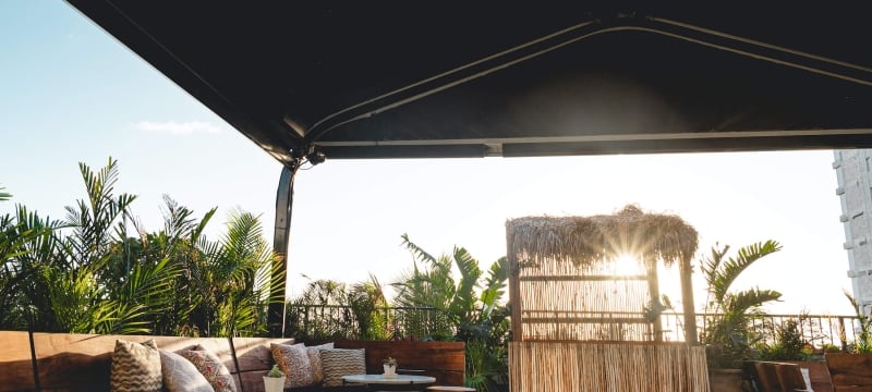 sun peaks through tiki bar at end of patio with disco ball 