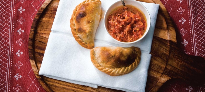 Empanadas on white napkin on wooden plate