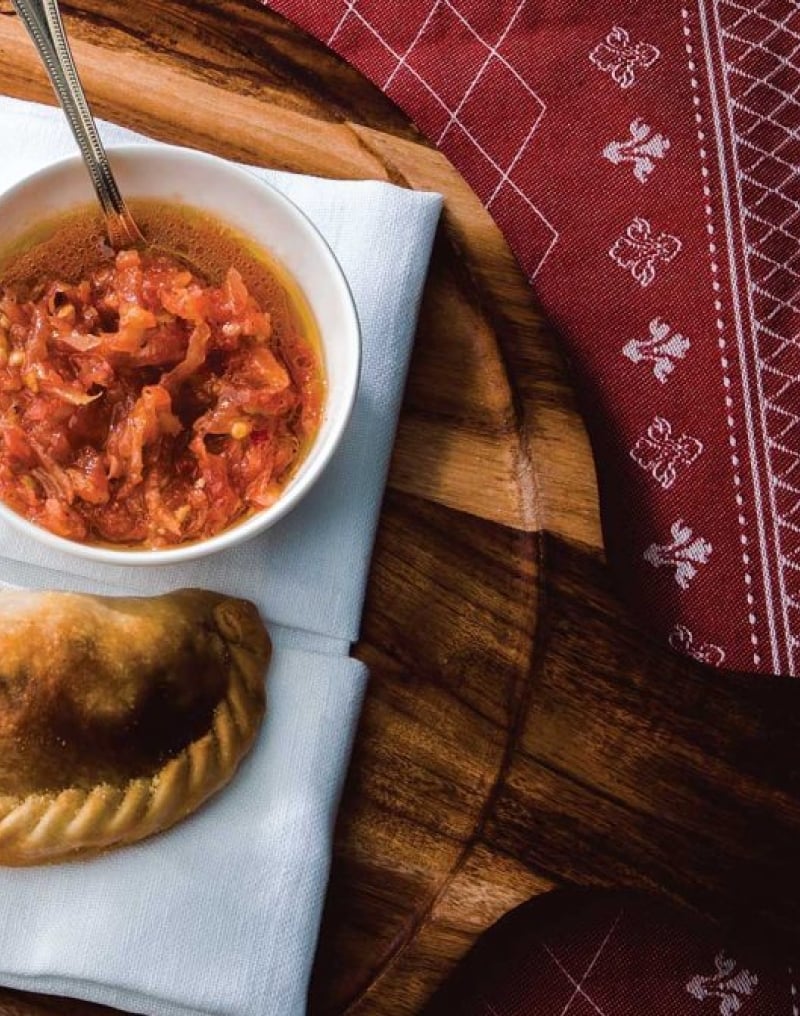 Empanadas on white napkin on wooden plate