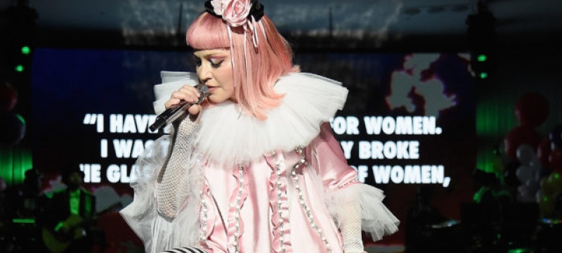 Madonna performs wearing pink wig, dress, and black & white stockings