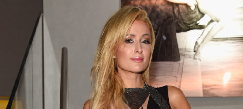 Paris Hilton stands on stairs wearing black dress