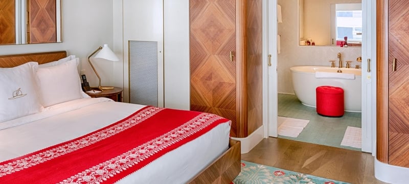 bed with view of bathtub in bathroom in the background