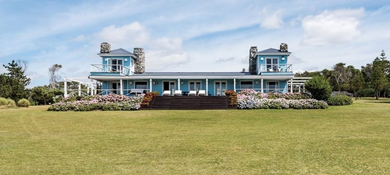 blue house sits on green lawn