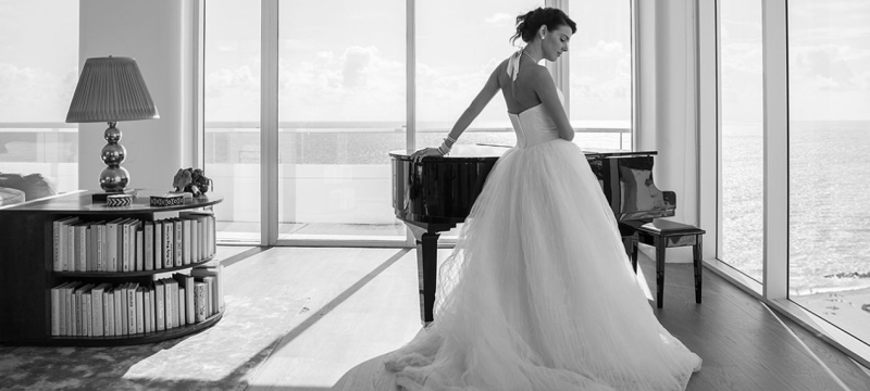 Bride in wedding dress leaning on grand piano