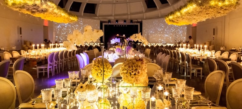 gold lit table setting with innumerable chairs and candles