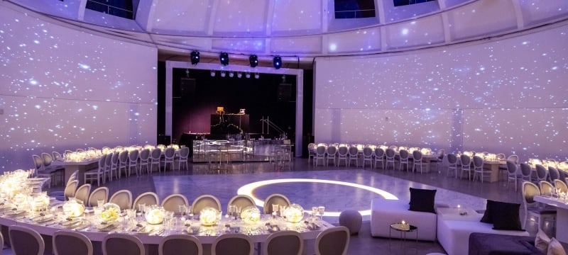 circular table for wedding reception with white flowers and purple lighting