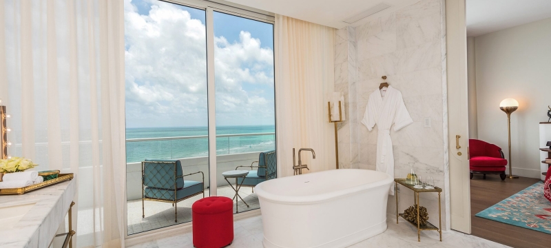 hotel bathroom with tub and balcony over the ocean