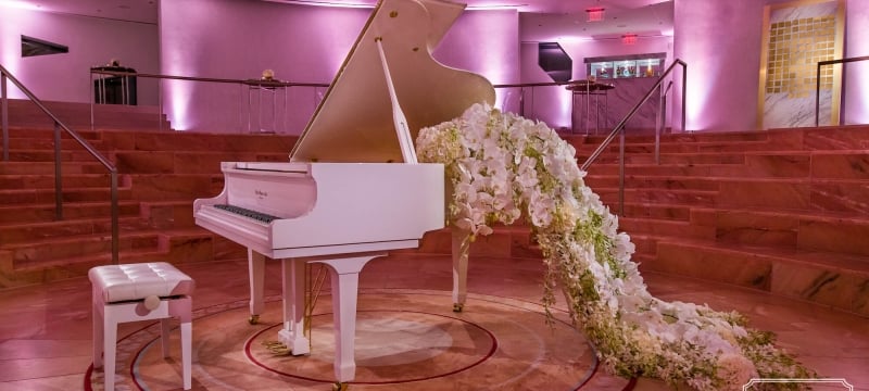 White piano with a train of flowers pouring out of the open lid