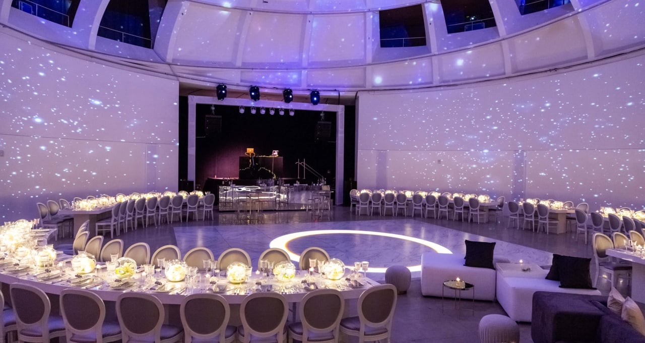 a large, round meeting room with tables, chairs, and a stage